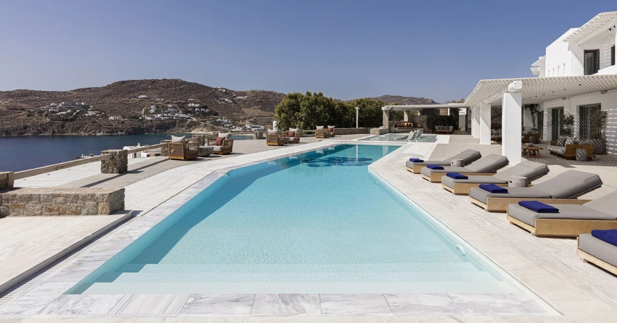 Luxury Mykonos villa with infinity pool overlooking the Aegean Sea during sunset, representing the cost of premium Mykonos travel in 2026